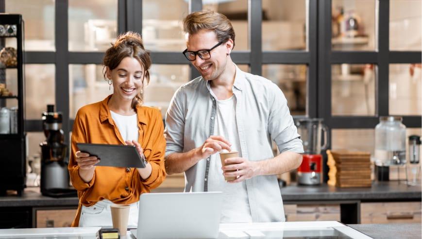 Two people stood in a kitchen looking at an iPad.