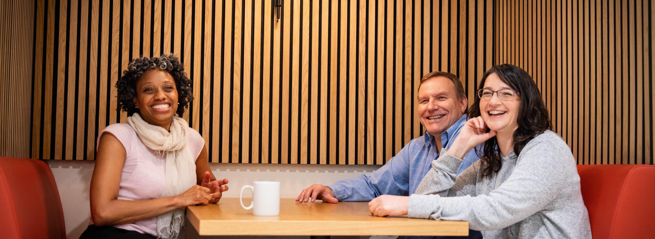 Group of people in an office meeting room with a wooden feel.