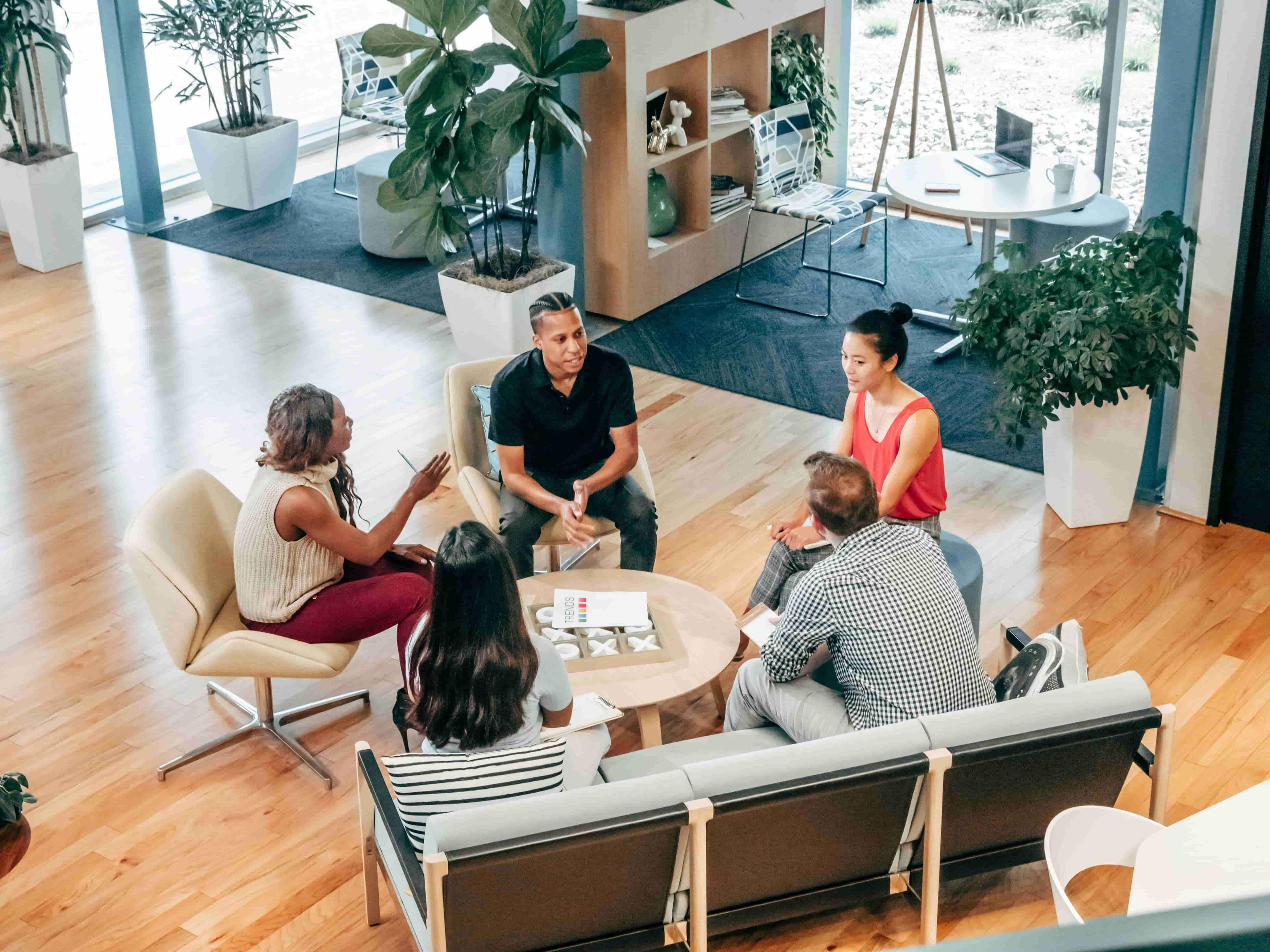 People sat in a modern office space on chairs and sofas around a table