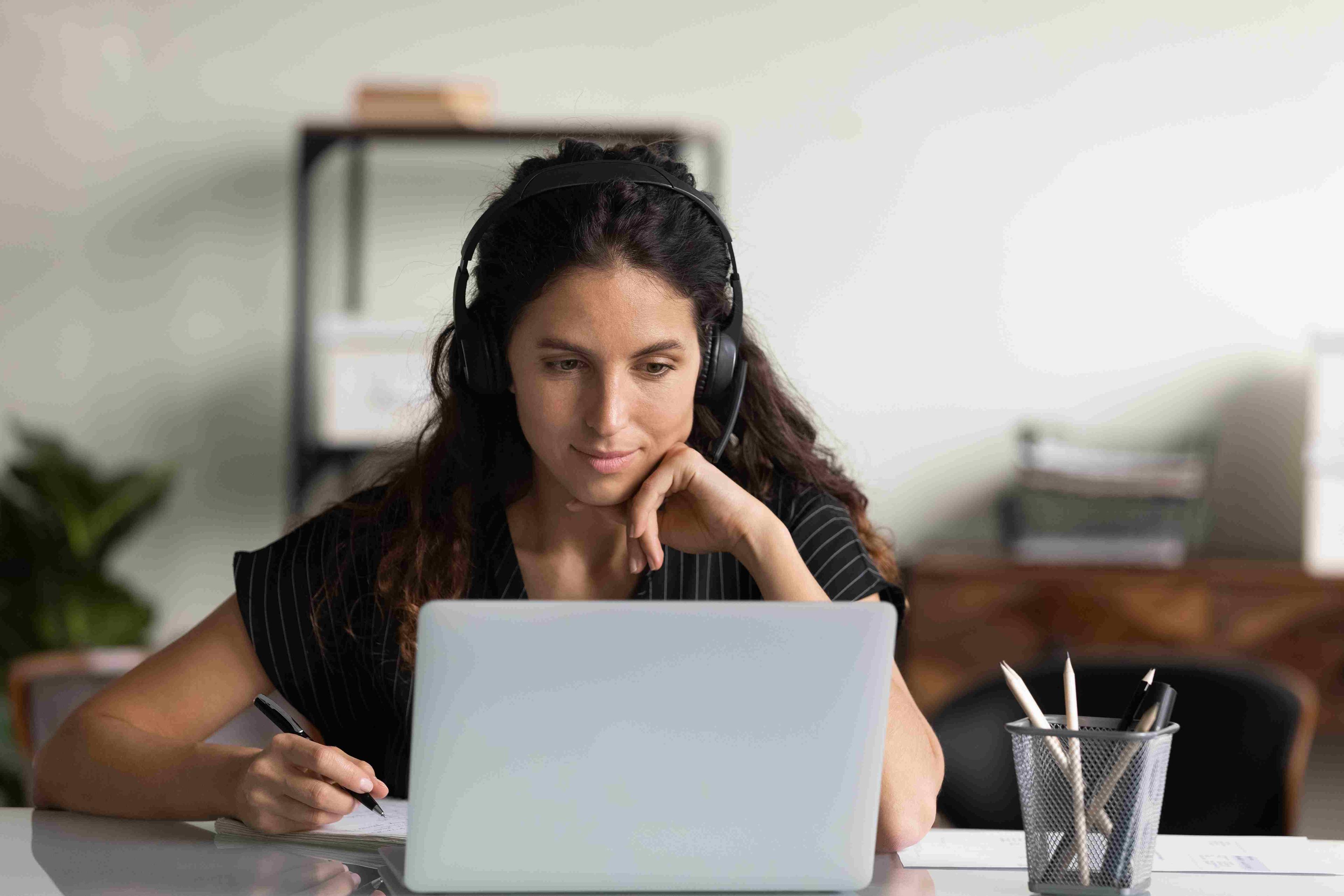 Woman working at desk with headphones and laptop