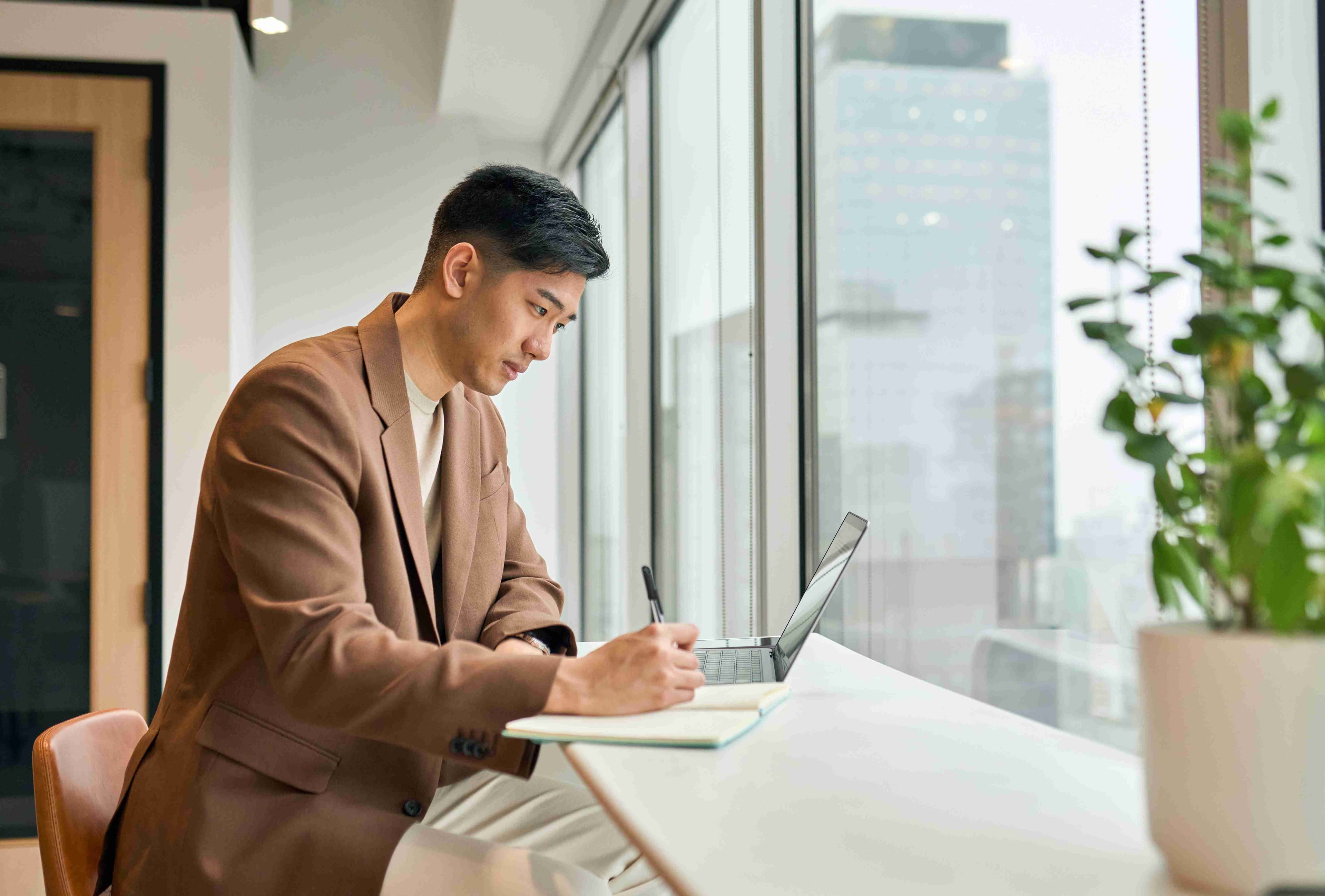 Man in brown blazer working at a window