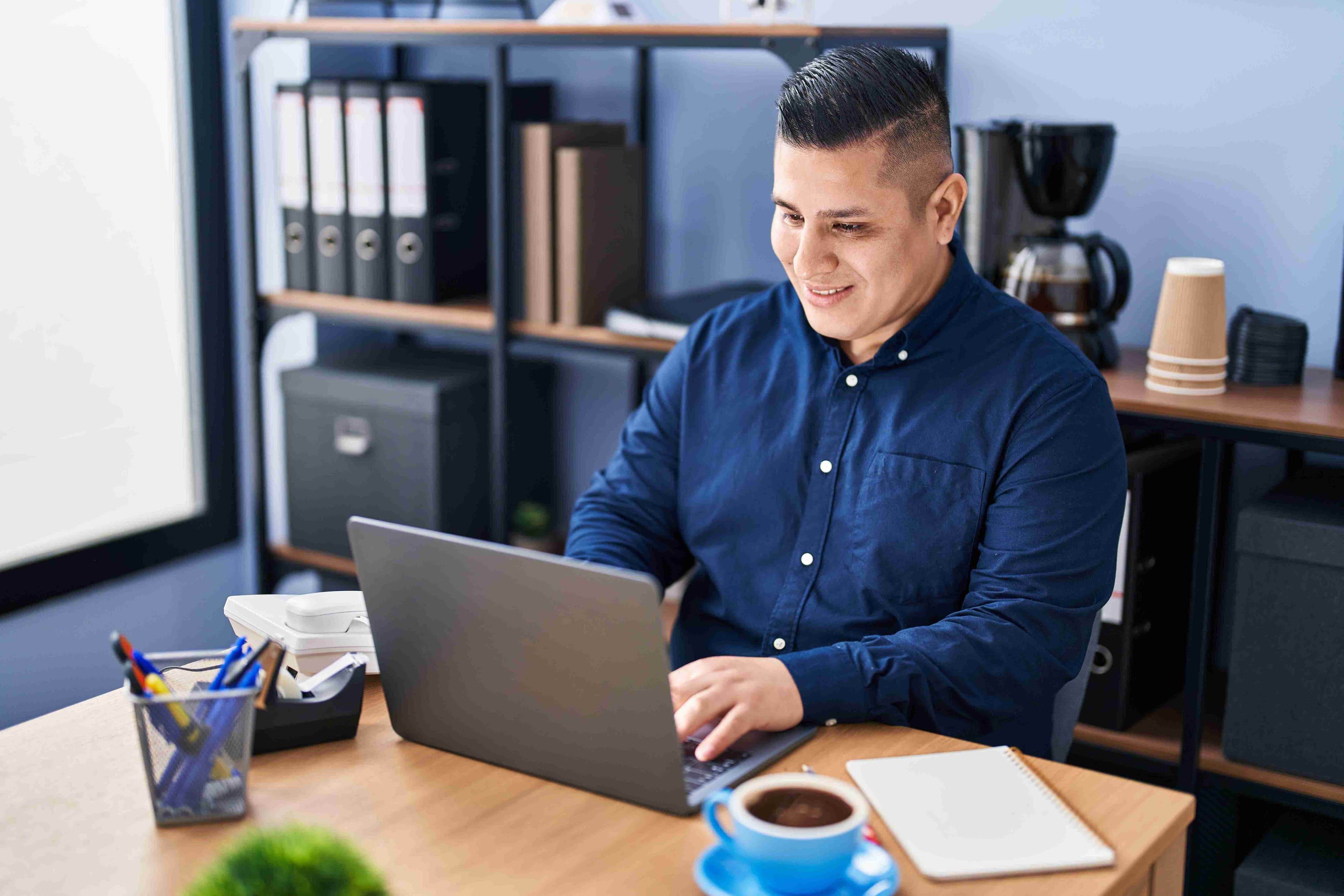 Man in blue shirt working at a laptop