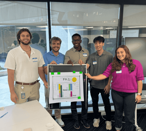 Diverse group of young people in front of a sign with a graph on it.