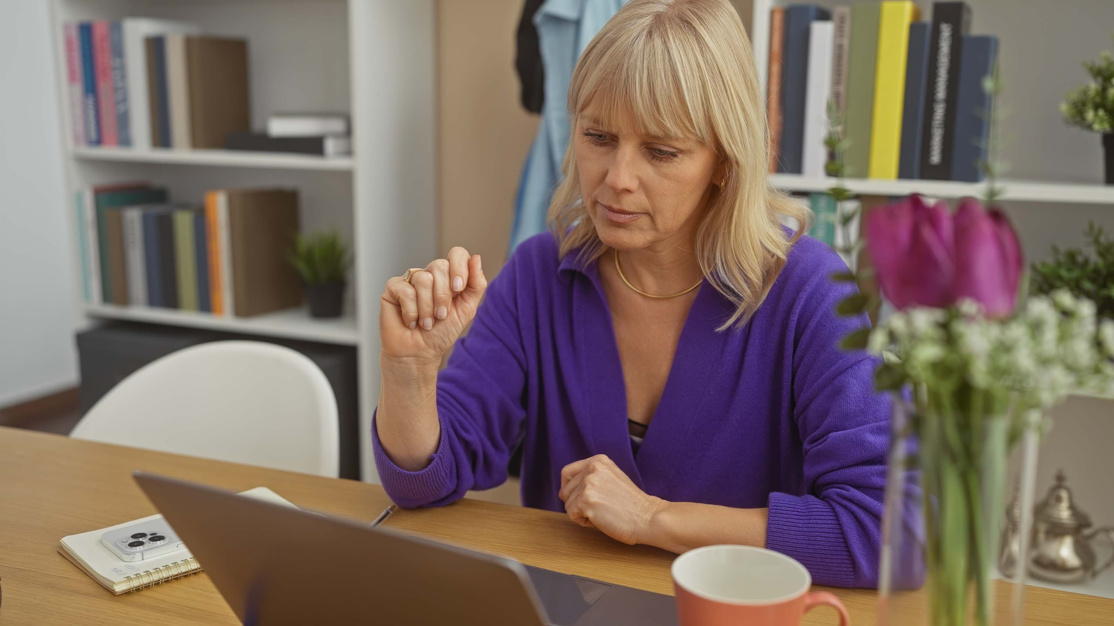 Woman in purple top with blonde hair working with a laptop