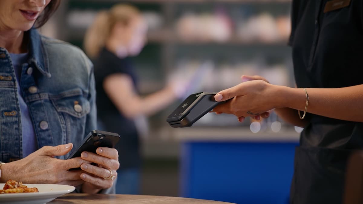 Woman paying by tapping card on card reader.